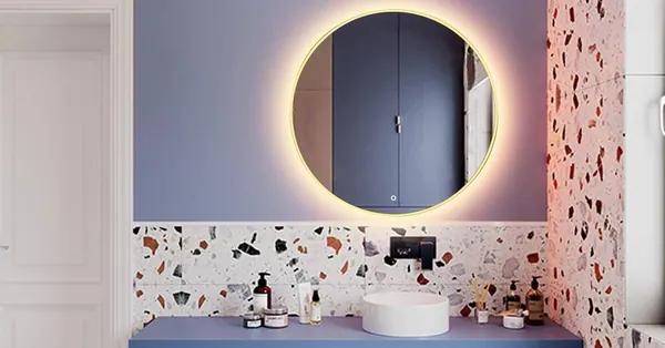 Miroir rond à lumière chaude au-dessus d'un lavabo et d'un mur en granito