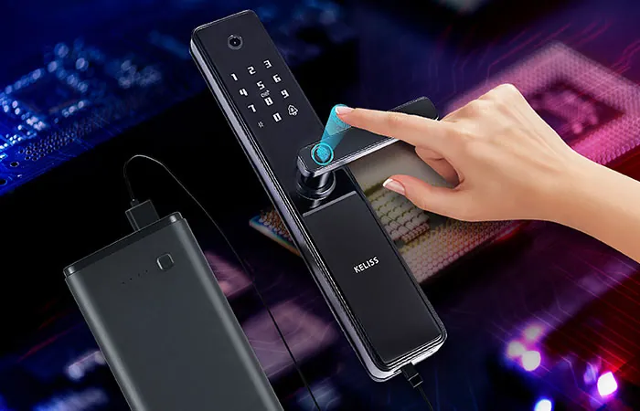 Batterie externe branchée sur une serrure connectée pendant qu'un doigt touche le lecteur d'empreintes